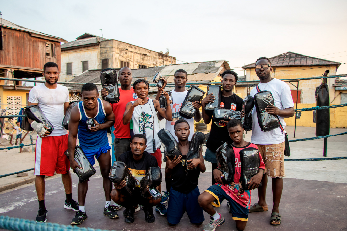 Boxers, coaches and Take Em Home travelers gathered inside a boxing ring in Ghana